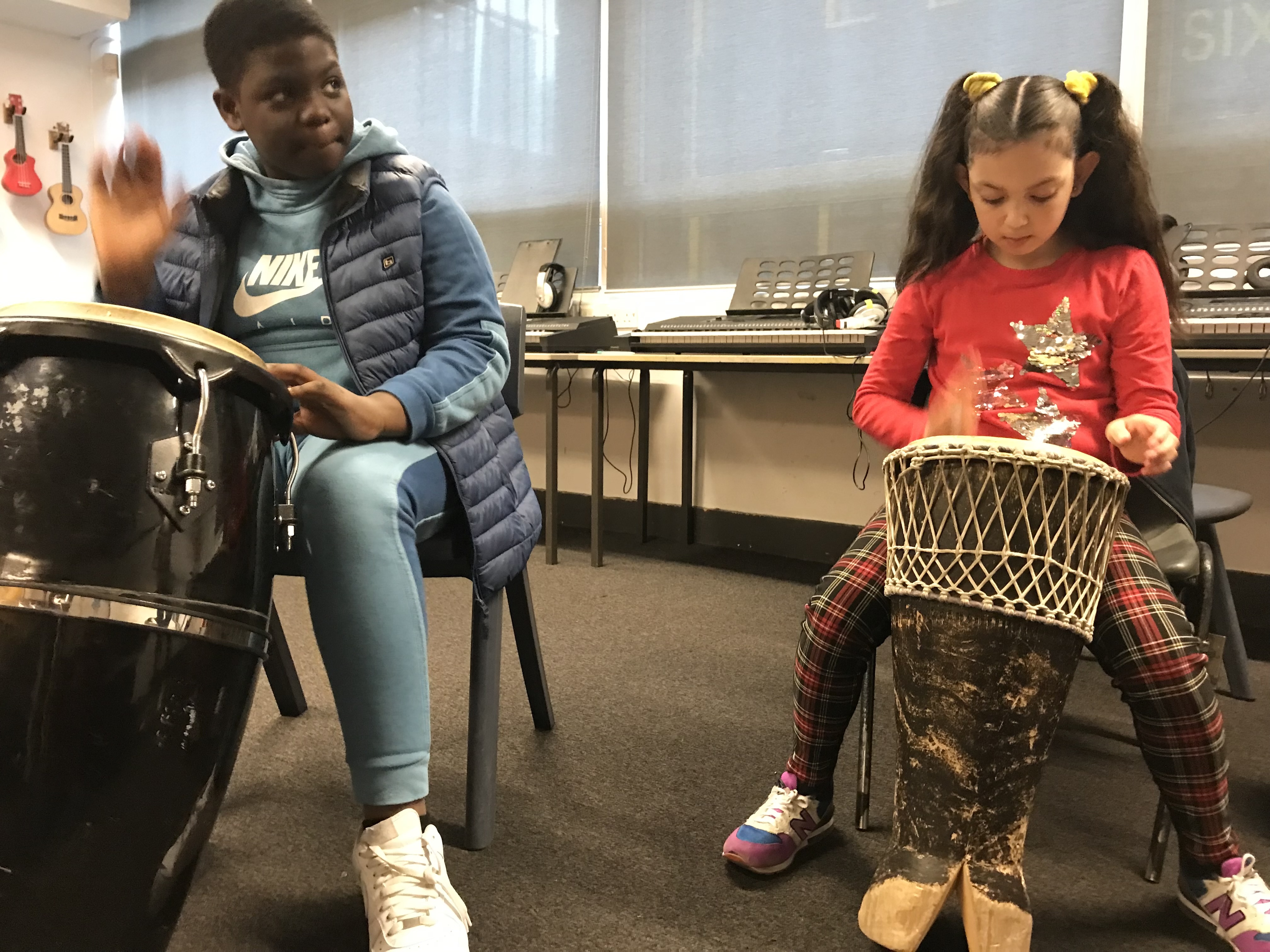 Two students playing Djembe Drums in Primary Orchestra.